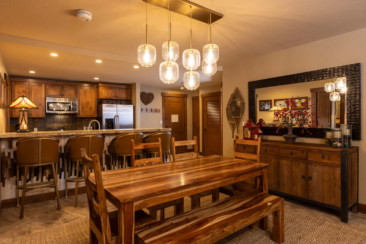 An inviting interior scene focusing on the dining table and kitchen bar, highlighted by elegant lighting and a decorative mirror. The setup is ideal for family dinners, celebrations, and relaxed gatherings, reinforcing the home’s welcoming nature.